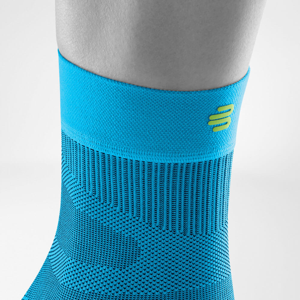 Detailansicht des oberen Bereiches des blauen Sportsleeves für das Sprunggelenk inklusive Gestrickverlauf und Logo